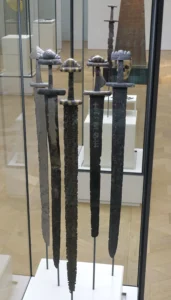 Vikingzwaarden uit de negende en tiende eeuw, gevonden in Noorwegen. De gevestvorm met halfronde knop en stevige pareerstang is karakteristiek voor de Petersen-typen H, S en X. Foto: Wikimedia Commons (Kulturhistorisk Museum Oslo, VIKINGR-tentoonstelling)